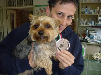 Yorkshire terrier gazdája karjában, aki egy érmet mutat